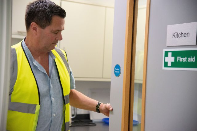 Someone in hi-vis checking a firedoor