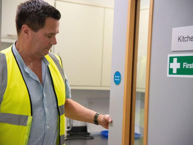Someone in hi-vis checking a firedoor